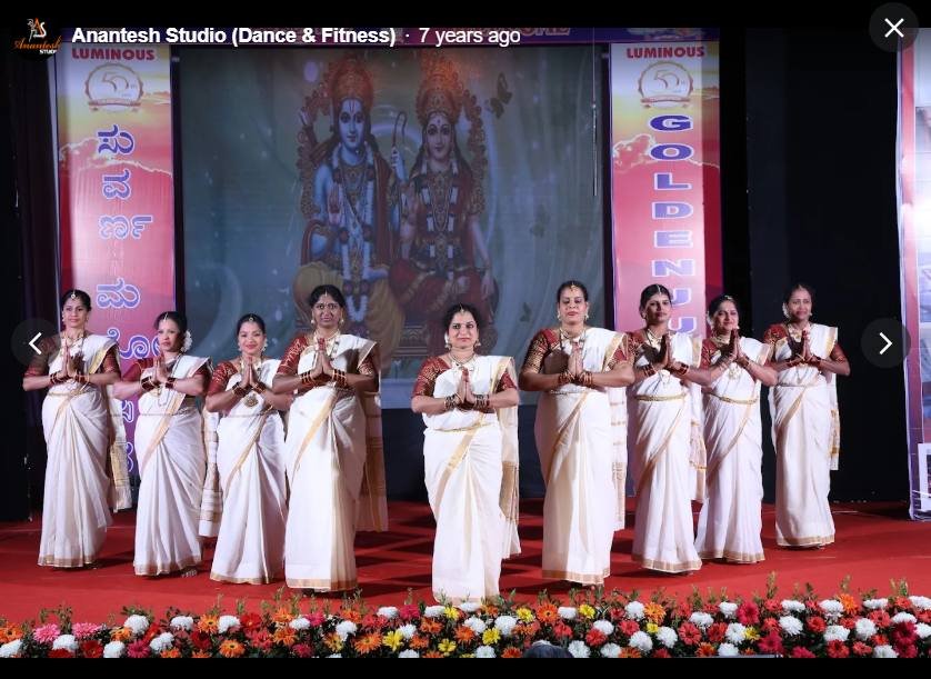 Classical dance group in white and gold sarees on stage